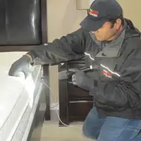 Bed bug inspection technician checking a mattress and bed frame for signs of infestation in Reno, NV