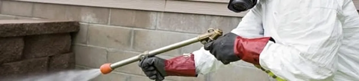 Pest control technician applying exterior insect treatment along a home foundation in Reno, NV