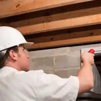Termite inspection technician checking a basement wall and framing for termite activity in Reno, NV
